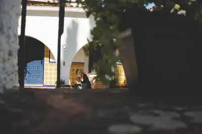 a woman sitting on a bench in front of a building at Casa con encanto in Corbera de Llobregat