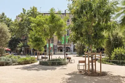 a park with benches and trees in front of a building at Enjoy Apartments Maria II in Barcelona