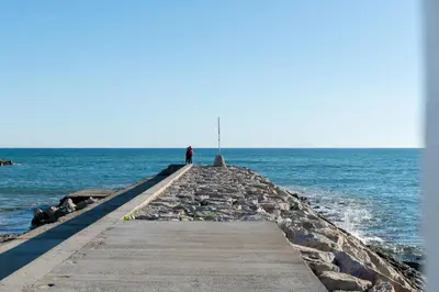 a person standing on a pier in the ocean at Vistamar 1: Primera línea de mar con encanto in Sitges