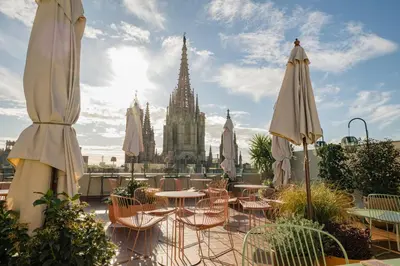 a patio with tables and umbrellas in front of a cathedral at Lamaro Hotel Barcelona - Preferred Hotels & Resorts - Lifestyle Collection in Barcelona