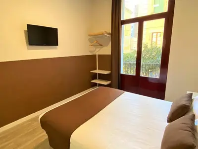 a bedroom with a bed with a window and a television at BCN Urbaness Hotels Bonavista in Barcelona