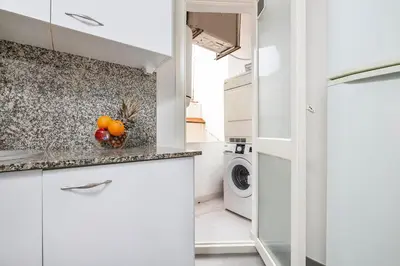 a kitchen with white cabinets and a washer and dryer at Apartments Sata Sagrada Familia Area in Barcelona