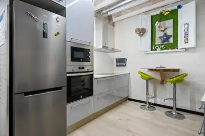 a kitchen with a stainless steel refrigerator and a table at Hauzify I Novavila Centre Rooms in Vilanova i la Geltrú