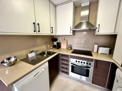 a kitchen with white cabinets and a sink and a stove at Acogedor apartamento entero in Terrassa