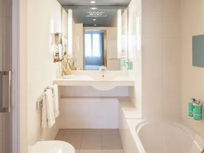 a white bathroom with a sink and a tub and a toilet at Novotel Barcelona Cornellà in Cornellà de Llobregat