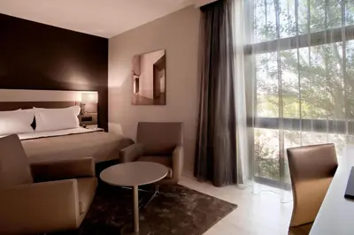 a bedroom with a bed and a table and a window at AC Hotel San Cugat by Marriott in Sant Cugat del Vallès