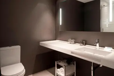 a bathroom with a sink and a toilet and a mirror at AC Hotel San Cugat by Marriott in Sant Cugat del Vallès