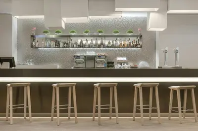 a bar with four bar stools in a restaurant at AC Hotel San Cugat by Marriott in Sant Cugat del Vallès