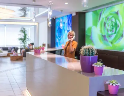 a woman standing behind a counter with potted plants at KAKTUS Hotel Kaktus Playa in Calella