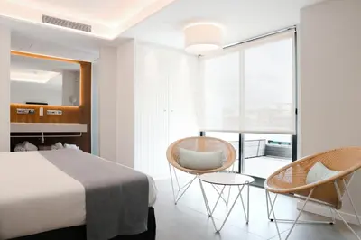 a bedroom with a bed and two chairs and a window at KAKTUS Hotel Kaktus Playa in Calella