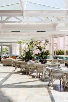a lobby with tables and chairs and plants at KAKTUS Hotel Kaktus Playa in Calella