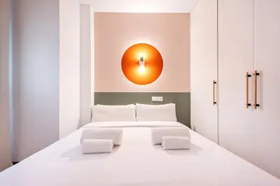 a bedroom with a white bed with a orange light on the wall at Sweett - Casa Bailen in Barcelona