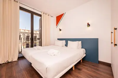 a bedroom with two beds and a large window at Sweett - Casa Bailen in Barcelona