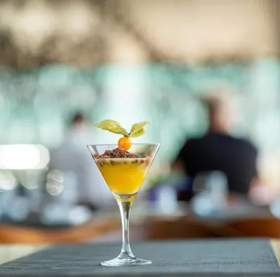 a cocktail with a basil leaf on top of a table at BAH Barcelona Airport Hotel in El Prat de Llobregat