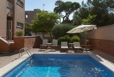 a swimming pool with a table and an umbrella at Canela Homes COSTA CASA AILA in Castelldefels