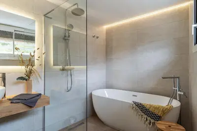 a bathroom with a tub and a glass shower at Canela Homes COSTA CASA AILA in Castelldefels