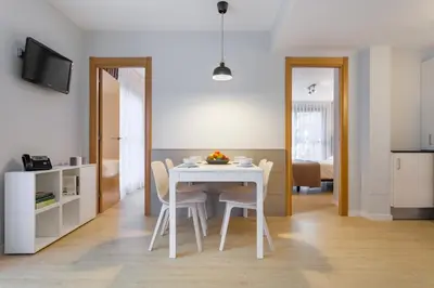 a kitchen and dining room with a white table and chairs at Apartamentos Royal Marina Gardens in Castelldefels