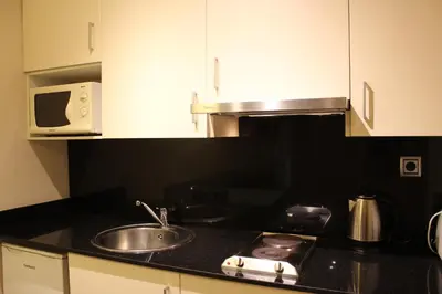 a kitchen with a sink and a microwave at Apartamentos Royal Marina Gardens in Castelldefels