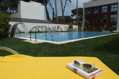 a book on a table next to a swimming pool at Apartamentos Royal Marina Gardens in Castelldefels