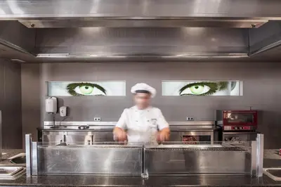 a chef standing in a kitchen with eyes on the wall at AQUA Hotel Promenade & Spa 4Sup in Pineda de Mar