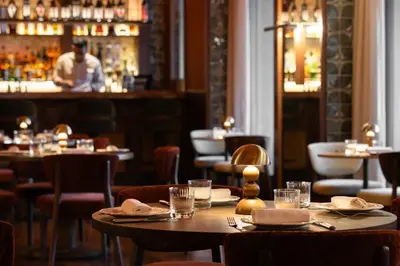 a restaurant with tables and chairs and a man in a bar at METT Barcelona GL - A Leading Hotel of the World in Barcelona