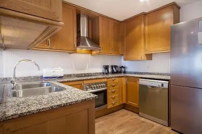 a kitchen with wooden cabinets and a stainless steel refrigerator at Suites4days Provenza Apartment in Barcelona