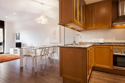 a kitchen with wooden cabinets and a table with chairs at Suites4days Provenza Apartment in Barcelona
