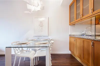 a kitchen with a glass table and white chairs at Suites4days Provenza Apartment in Barcelona