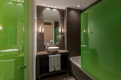 a green bathroom with a sink and a mirror at Room Mate Carla, Barcelona in Barcelona