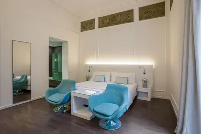 a bedroom with a bed and two blue chairs at Room Mate Carla, Barcelona in Barcelona