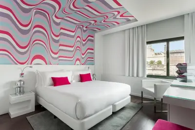 a bedroom with a white bed and a colorful mural at Room Mate Carla, Barcelona in Barcelona