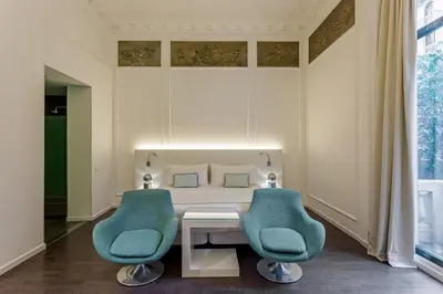 a room with a table and two blue chairs at Room Mate Carla, Barcelona in Barcelona