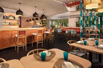 a restaurant with tables and chairs and a bar at NH Collection Barcelona Constanza in Barcelona