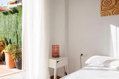 a white bedroom with a bed and a window at ApartEasy - Private Terrace, 3-Bedroom Apartment in Barcelona