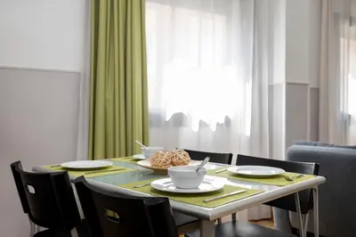 a dining room table with chairs and a table with dishes at Apartments Sata Park Guell Area in Barcelona