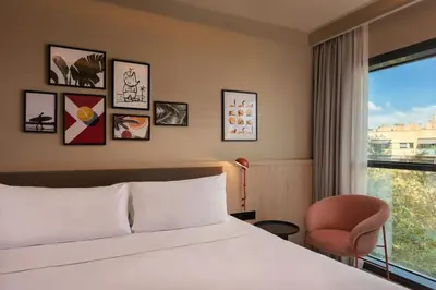 a hotel room with a bed and a chair and a window at Four Points by Sheraton Barcelona Diagonal in Barcelona
