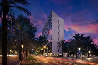 a tall building with palm trees in front of a street at Four Points by Sheraton Barcelona Diagonal in Barcelona