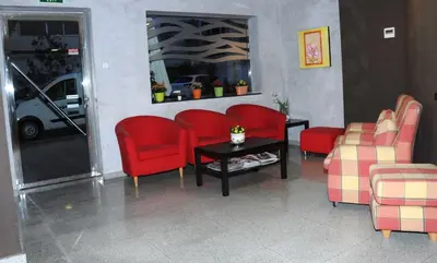 a waiting room with red chairs and a table at Llagotel in La Llagosta