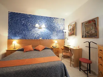 a bedroom with a bed and a blue wall at Hotel Montserrat in Sitges