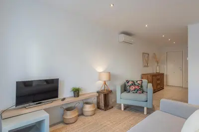 a living room with a television and a blue chair at Mare Nostrum: En el corazón de Sitges in Sitges
