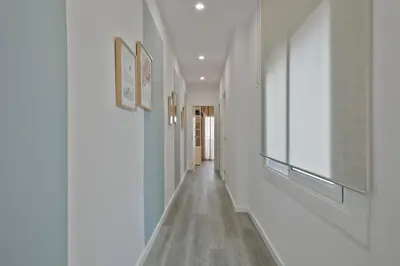 a hallway with white walls and wood floors and paintings at Alcam Badalona Roger in Badalona
