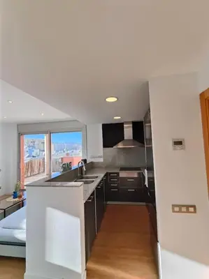 a kitchen with black cabinets and a large window at Large terrace luxury apartment in Sant Adria de Besos