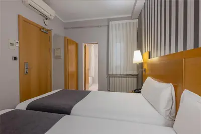 a hotel room with a large white bed and a window at Hotel Lyon in Barcelona