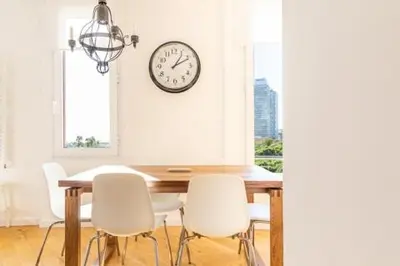 a dining room table with white chairs and a clock on the wall at Idyllic apartment in BCN beach in Barcelona