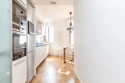a kitchen with white appliances and a wooden floor at Idyllic apartment in BCN beach in Barcelona