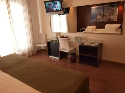 a hotel room with a desk and a tv on the wall at Galeón in Sitges