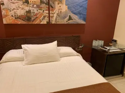 a bedroom with a white bed with a painting on the wall at Galeón in Sitges