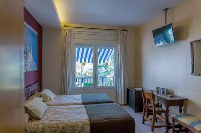 a bedroom with a bed and a desk and a window at Galeón in Sitges