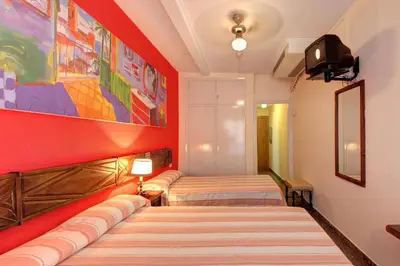 a room with two beds and a tv on a wall at El Cid in Sitges