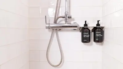 a shower with a shower head and two soap bottles at Chic & Basic Tallers Hostal in Barcelona